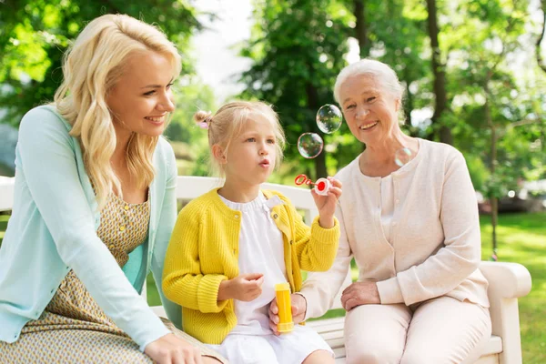 Lycklig familj blåser såpbubblor på park — Stockfoto