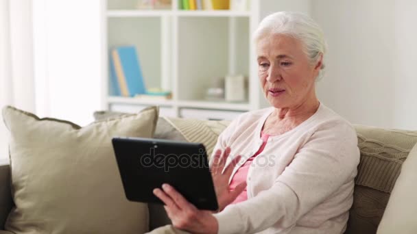 Vieille femme avec tablette pc ayant chat vidéo à la maison — Video