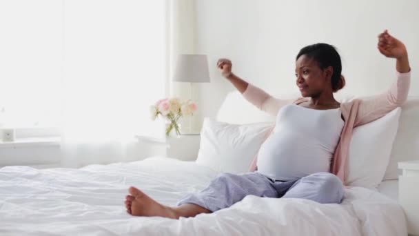 Šťastné těhotenství Afričanka, táhnoucí se v posteli — Stock video
