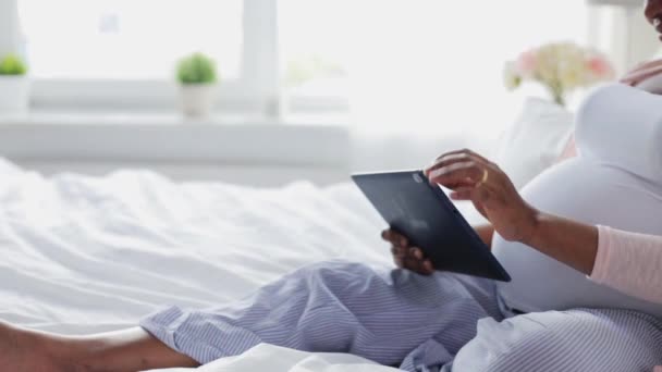 Счастливая беременная женщина с планшетным ПК в постели — стоковое видео