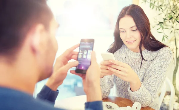 Casal feliz com smartphones bebendo chá no café — Fotografia de Stock