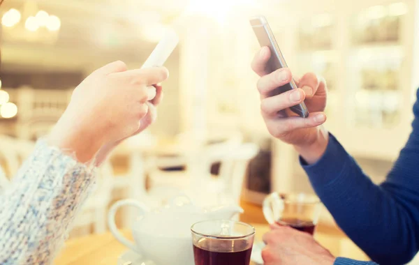 Закрыть пару со смартфонами в кафе — стоковое фото