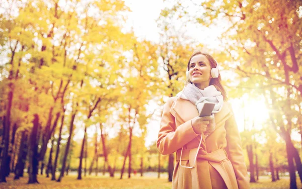 Mujer con smartphone y auriculares en el parque de otoño —  Fotos de Stock