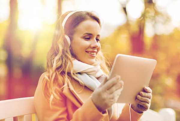 Mulher com tablet pc e fones de ouvido no parque de outono — Fotografia de Stock