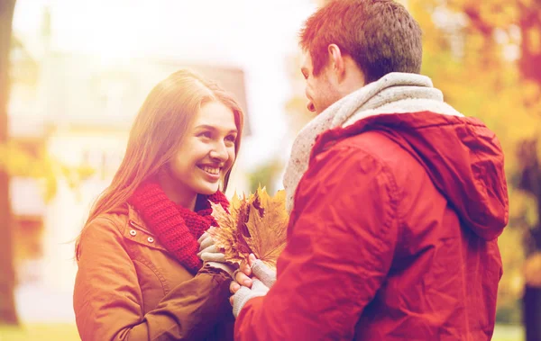 Lyckliga par med maple lämnar i höst park — Stockfoto
