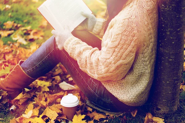 Woman with book drinking coffee in autumn park — Stock Photo, Image