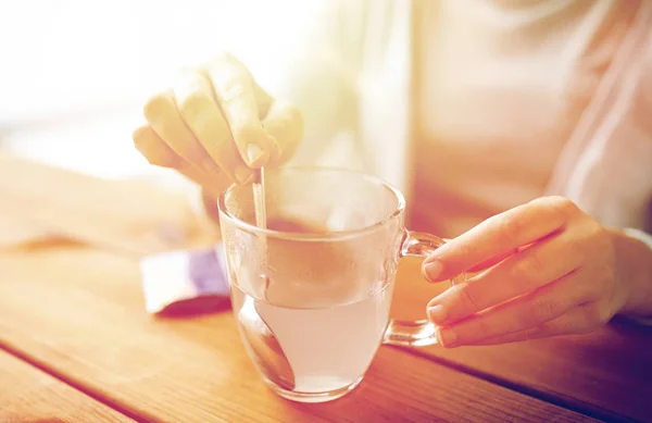 Kvinna under omrörning medicinering i kopp vatten — Stockfoto