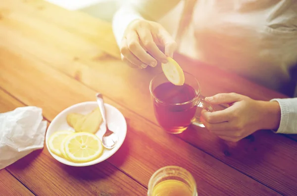 Primer plano de la mujer añadiendo limón a la taza de té — Foto de Stock