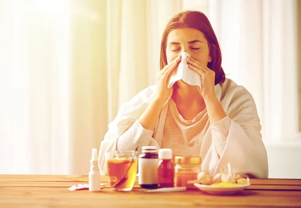 Zieke vrouw met medicijnen snuit neus af te vegen — Stockfoto