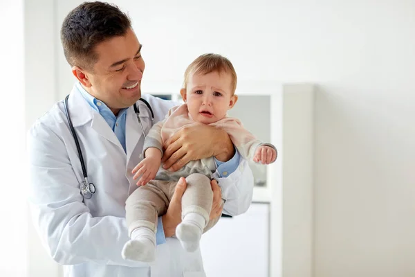 Glücklicher Arzt oder Kinderarzt mit Baby in der Klinik — Stockfoto