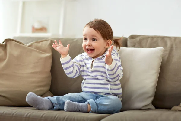 Feliz sorrindo bebê menina sentado no sofá em casa — Fotografia de Stock