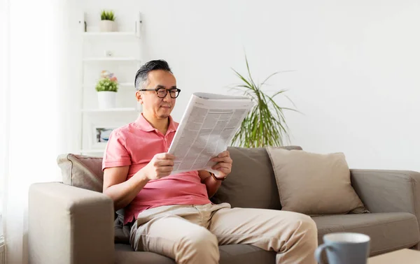 Evde Gazete okurken gözlüklü Asyalı adam — Stok fotoğraf