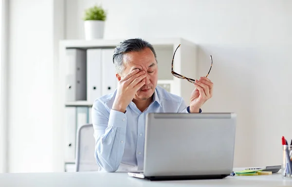 Hombre de negocios cansado con gafas en el ordenador portátil en la oficina —  Fotos de Stock