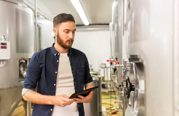 Hombre con tableta PC en la fábrica de cerveza artesanal o planta de cerveza — Foto de Stock