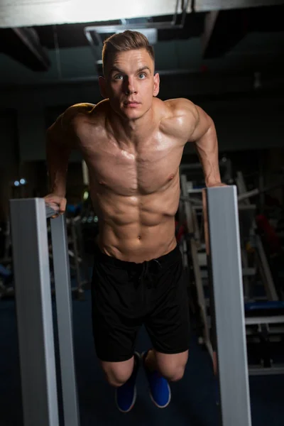Muž dělá triceps dip na paralelní bary v tělocvičně — Stock fotografie