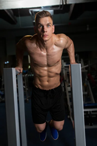 Uomo facendo tricipiti tuffo su barre parallele in palestra — Foto Stock