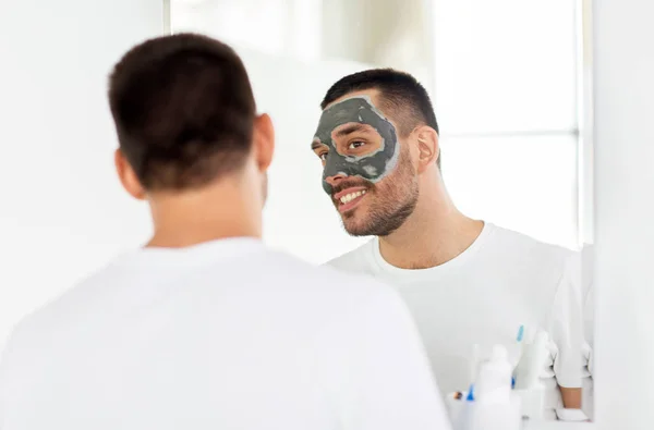 Young man with clay mask on face at bathroom — Stock Photo, Image