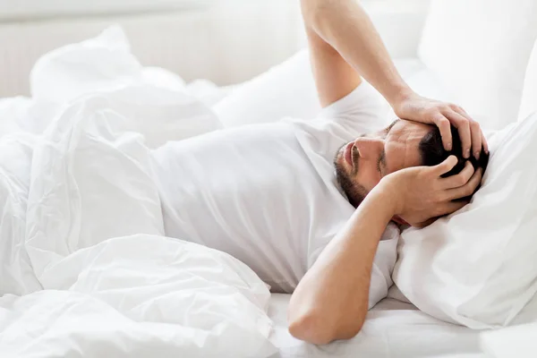 Adam yatakta evde baş ağrısı acı — Stok fotoğraf