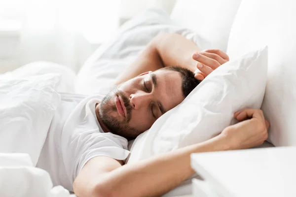 Мужчина спит в постели дома — стоковое фото