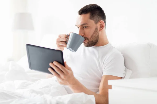 Homem com tablet pc beber café na cama em casa — Fotografia de Stock