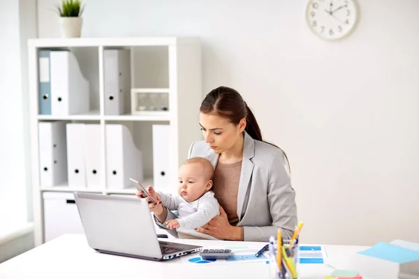 Affärskvinna med baby och smartphone på kontor — Stockfoto