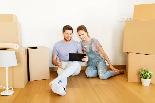 Par med lådor och tablet pc flyttar till nytt hem — Stockfoto