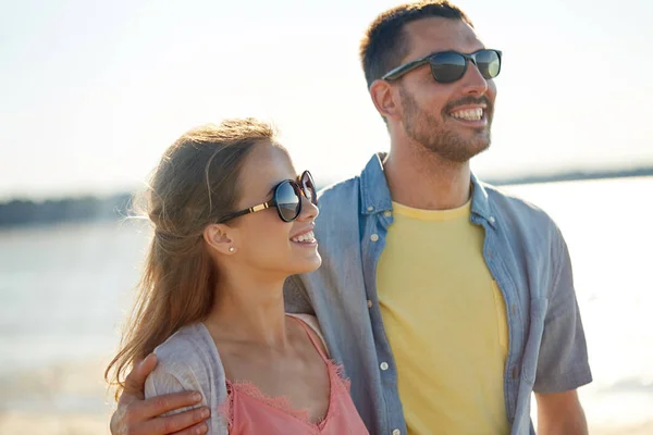 Felice coppia in occhiali da sole che si abbraccia sulla spiaggia estiva — Foto Stock