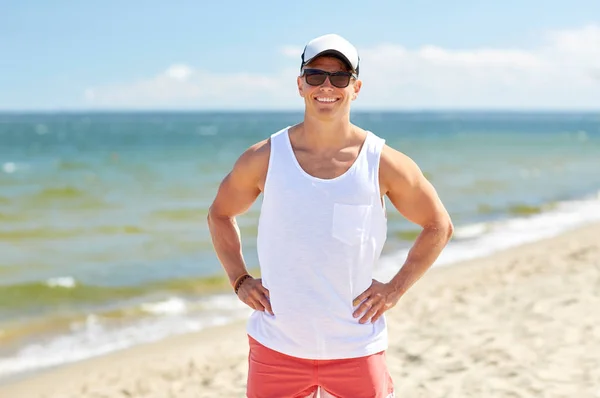 Glimlachende jonge man in een zonnebril op het zomerstrand — Stockfoto