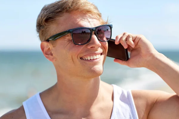 Sonriente hombre llamando en el teléfono inteligente en la playa de verano — Foto de Stock