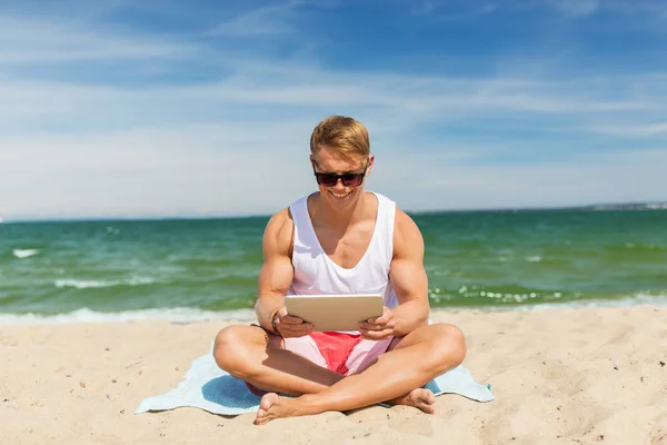 Щасливий усміхнений молодий чоловік з планшетним ПК на пляжі — стокове фото