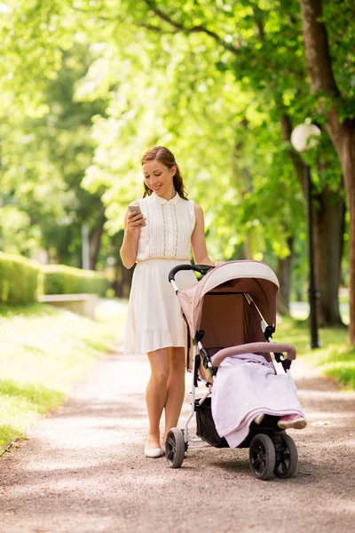 智能手机与婴儿小推车在公园快乐妈妈 — 图库照片