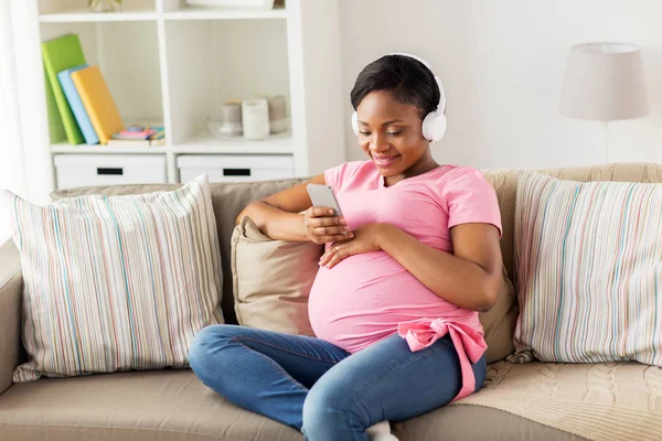 Femme enceinte dans un casque avec smartphone — Photo