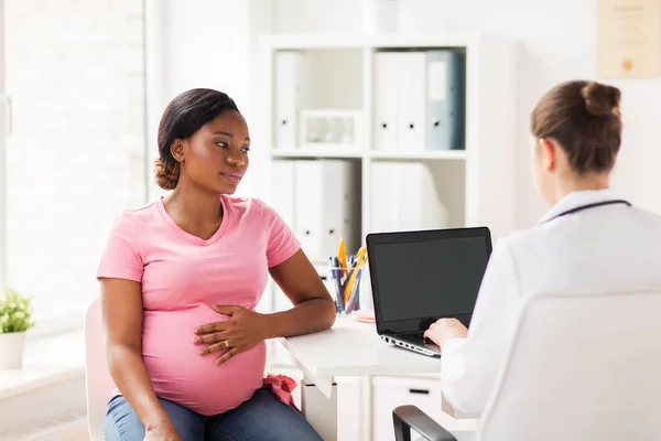 Doctor with laptop and pregnant woman at clinic — Stock Photo, Image