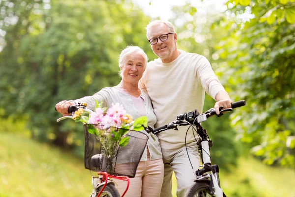 Gelukkige senior paar met fietsen in zomer park — Stockfoto