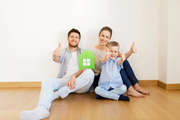 Сім'я з зеленим будинком, що показує великі пальці вдома Стокове Зображення