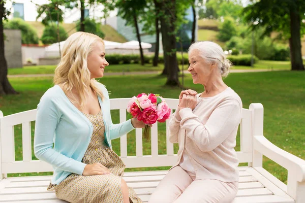 Dotter att ge blommor till senior mor på park — Stockfoto