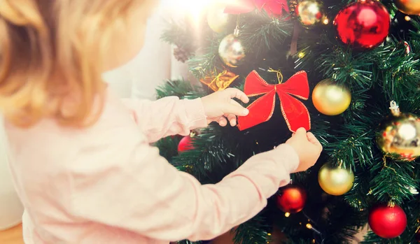 Nahaufnahme eines kleinen Mädchens, das den Weihnachtsbaum schmückt — Stockfoto