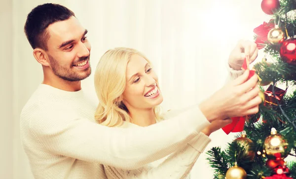Happy couple decorating christmas tree at home — Stock Photo, Image