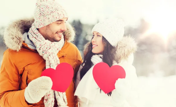 Casal feliz com corações vermelhos sobre paisagem de inverno — Fotografia de Stock