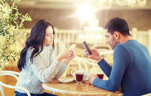 Pareja con teléfonos inteligentes beber té en la cafetería — Foto de Stock