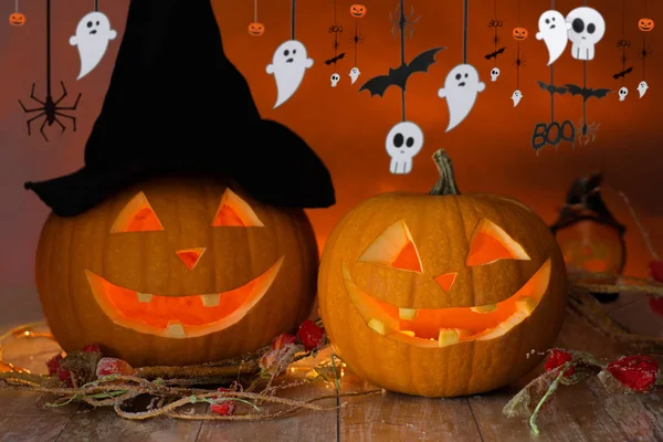 Carved pumpkins in witch hat and halloween garland — Stock Photo, Image