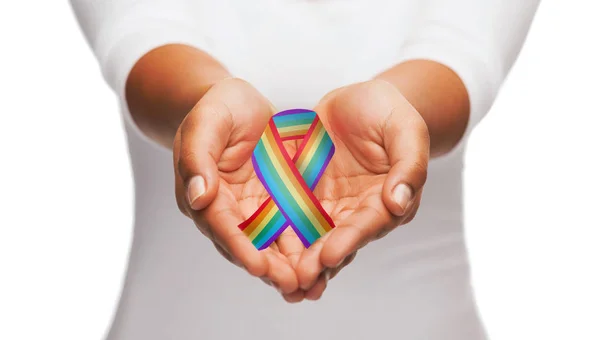 Hands holding rainbow gay pride awareness ribbon — Stock Photo, Image