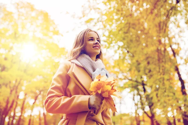 Hermosa mujer con hojas de arce en el parque de otoño — Foto de Stock