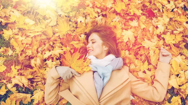 Krásná šťastná žena ležící na podzimní listí — Stock fotografie