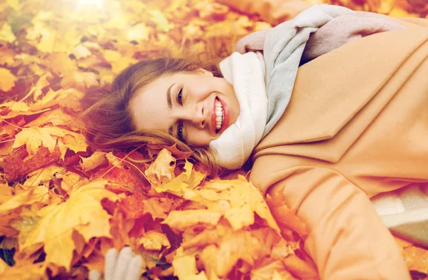 Hermosa mujer feliz acostada en hojas de otoño — Foto de Stock