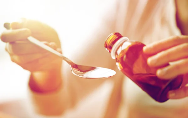 Mujer vertiendo medicamentos de botella en cuchara — Foto de Stock