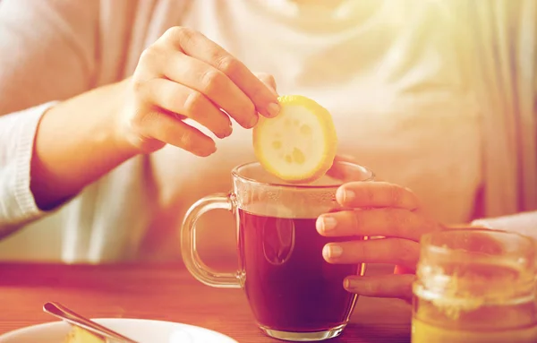 Primo piano della donna che aggiunge limone al tè con miele — Foto Stock