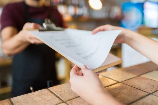 Bartender showing menu to customer at bar — Stock Photo, Image