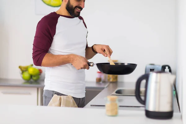 Человек с сковородой приготовления пищи на домашней кухне — стоковое фото