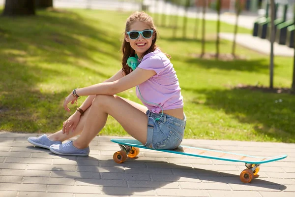 Menina adolescente feliz com fones de ouvido e longboard — Fotografia de Stock